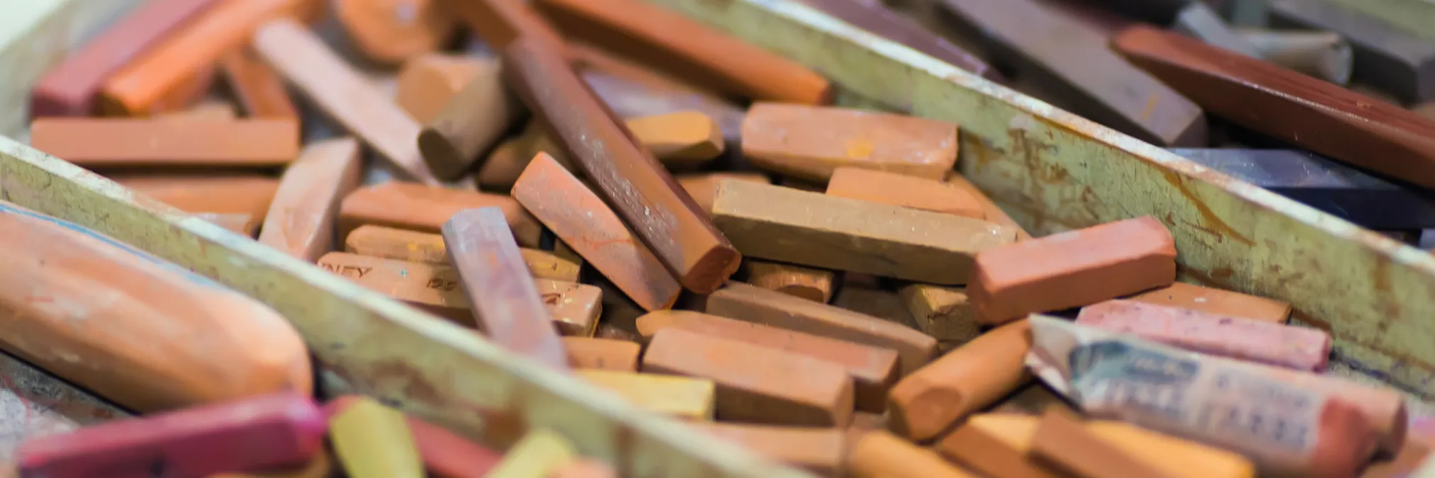 Photo of various sanguine-colored pastels and sticks representing the materials used for the mentored drawing sessions in DFW area.